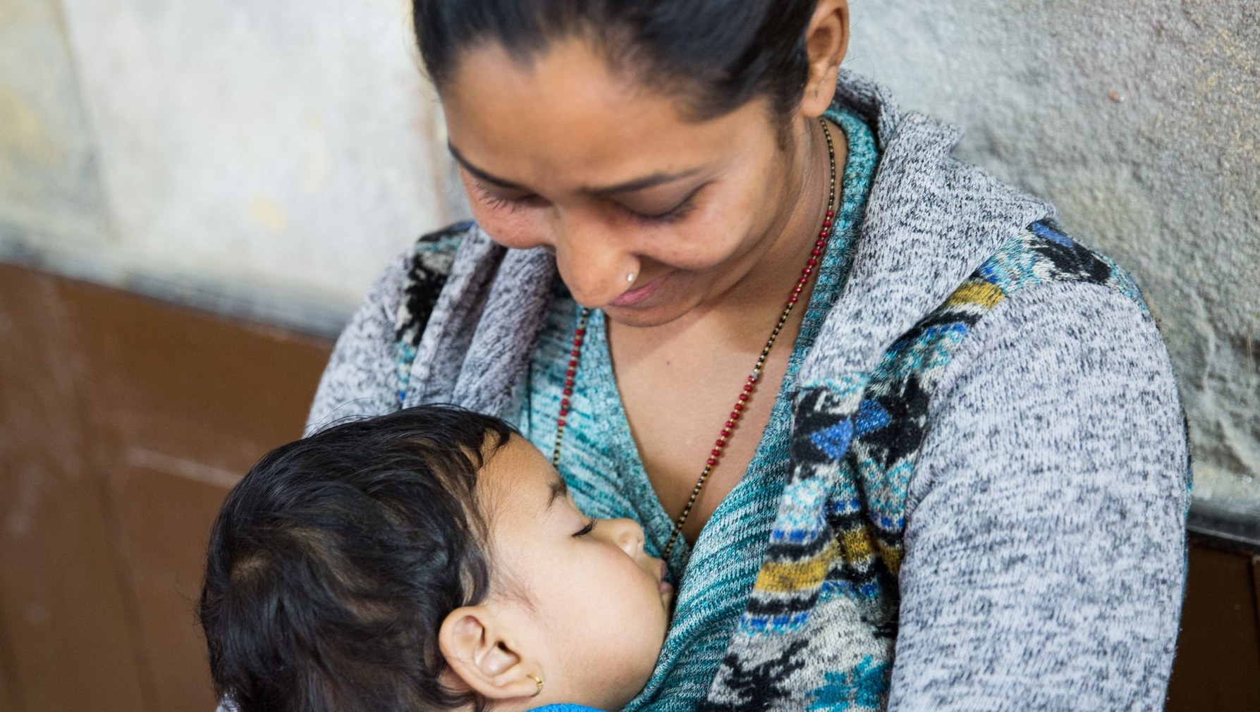 Woman smiling at child sleeping on her chest